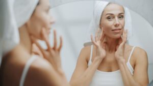 Beautiful middle-aged woman looking at herself in mirror