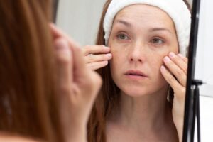 Woman looking in mirror, concerned about wrinkles